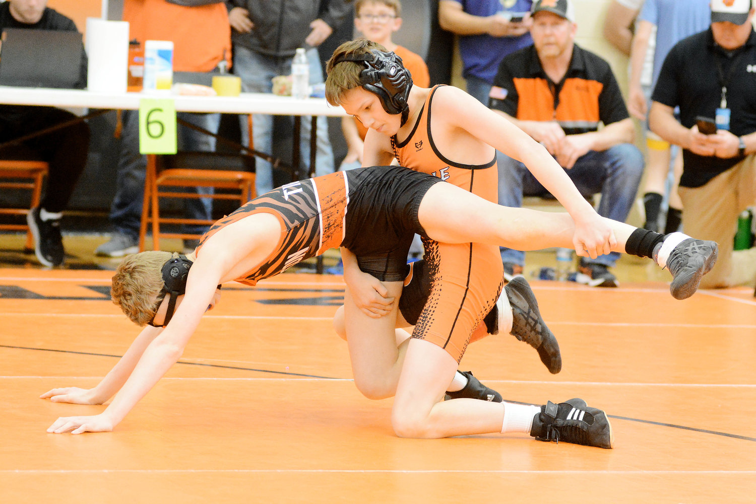 Mason Turner (solid orange singlet) gains control of Macon’s Ben Seiler during their second-round consolation match at 100 pounds in the 12-and-under division during Saturday’s Missouri USA District 7 Wrestling Tournament hosted by Owensville High School. Turner won a 6-2 decision over his orange and black opponent.